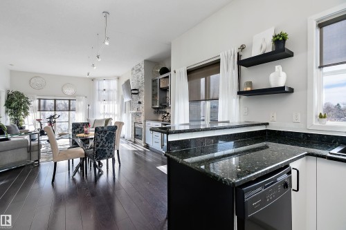 Recently renovated kitchen featuring dark stone countertops, dark wood finished floors, plenty of natural light, and dishwashing machine - 302 10905 109 Street, Edmonton, AB 