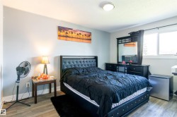 Bedroom featuring wood-finish flooring, light grey painted walls, and a ceiling-mounted light fixture - 