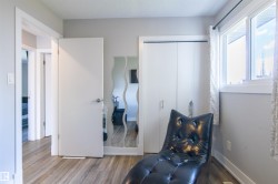 Neutral gray walls featuring wood-finish flooring, a double window with white trim, and a built-in closet with white bifold doors - 