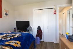 Bedroom featuring wood-finish flooring, white walls, and a built-in closet with white bifold doors - 