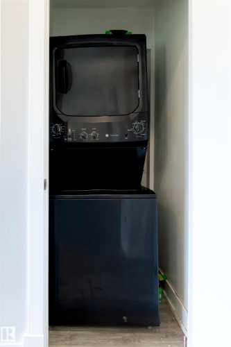 Laundry closet featuring a black stacked washer and dryer unit - 7115 39A Avenue, Edmonton, AB - Indoor Photo Showing Laundry Room