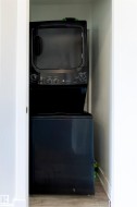 Laundry closet featuring a black stacked washer and dryer unit - 
