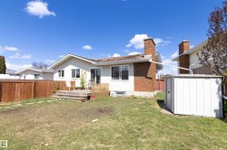 Expansive rear yard featuring a wooden privacy fence and a white storage shed - 