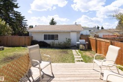 Backyard featuring a wooden deck with lattice accents, a paved stone walkway, and a detached structure with a pitched roof - 