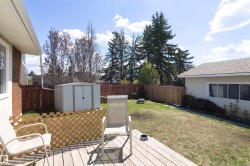 Decked backyard space with a storage shed, wood privacy fence, and mature trees - 