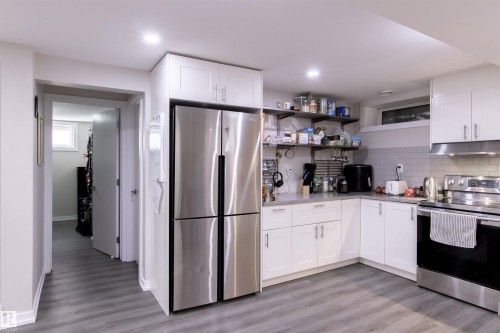 Contemporary kitchen featuring white cabinetry, stainless steel appliances, a subway tile backsplash, and light wood-finish flooring - 7115 39A Avenue, Edmonton, AB - Indoor Photo Showing Kitchen