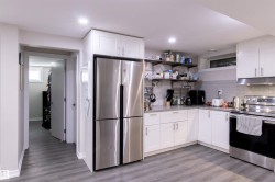 Contemporary kitchen featuring white cabinetry, stainless steel appliances, a subway tile backsplash, and light wood-finish flooring - 