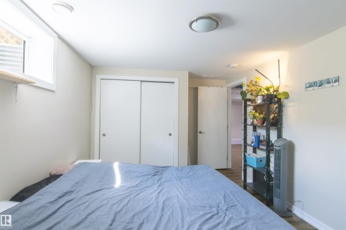 Room featuring wood-finish flooring, a flush-mount ceiling light fixture, a window with horizontal blinds, and double sliding closet doors - 7115 39A Avenue, Edmonton, AB - Indoor Photo Showing Bedroom