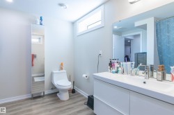 Modern bathroom with wood-finish flooring, a white floating vanity, and a large wall-mounted mirror - 