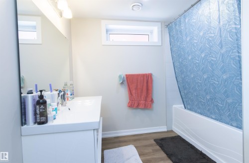 Bathroom featuring a white vanity with integrated sink, rectangular mirror, and overhead light fixture - 7115 39A Avenue, Edmonton, AB - Indoor Photo Showing Bathroom