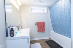 Bathroom featuring a white vanity with integrated sink, rectangular mirror, and overhead light fixture - 