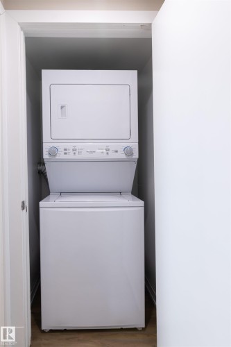 Stacked white laundry appliances within a dedicated utility closet - 7115 39A Avenue, Edmonton, AB - Indoor Photo Showing Laundry Room