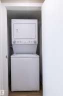 Stacked white laundry appliances within a dedicated utility closet - 