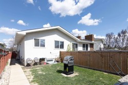 Rear exterior featuring a stucco finish, multiple windows, and a basement window - 