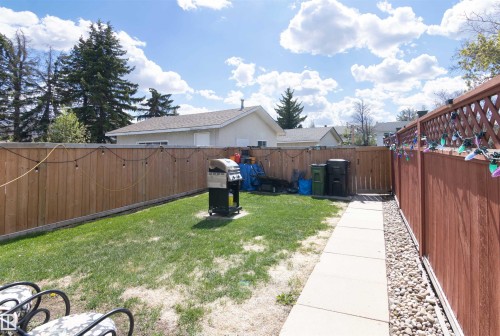 Fenced backyard featuring a manicured lawn, concrete pathway, and decorative gravel - 7115 39A Avenue, Edmonton, AB - Outdoor