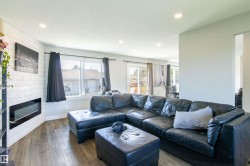 Living room featuring wood-finish flooring, recessed lighting, and a modern wall-mounted fireplace with shiplap surround - 