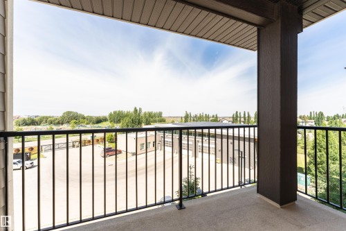 Private balcony featuring a concrete floor, black metal railing, and a dark brown support column - 404 12045 22 Avenue, Edmonton, AB 