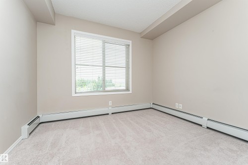 Room with neutral wall paint and light-colored carpet flooring - 404 12045 22 Avenue, Edmonton, AB 