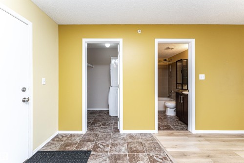 Laundry area and bathroom featuring coordinating patterned tile flooring - 404 12045 22 Avenue, Edmonton, AB 