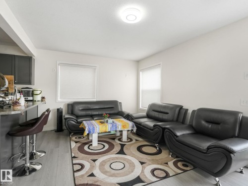 Open-concept living space featuring wood-finish flooring, white walls, and multiple windows with roller blinds - 18 230 Edwards Drive, Edmonton, AB 