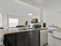 Kitchen island with dark cabinetry, dual stainless steel sinks, and a light-toned countertop - 