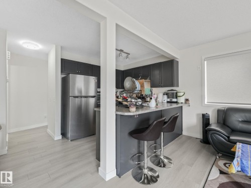 Kitchen with dark cabinetry and stainless steel refrigerator - 18 230 Edwards Drive, Edmonton, AB 