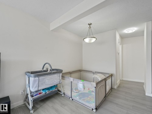 Interior space featuring light grey wood-finish flooring, white walls, and a recessed ceiling beam - 18 230 Edwards Drive, Edmonton, AB 