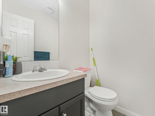 Bathroom vanity with a dark wood-finish cabinet, a light-toned countertop, and an integrated white porcelain sink - 18 230 Edwards Drive, Edmonton, AB 
