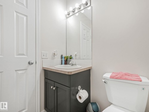 Vanity with a laminate countertop and an integrated sink, featuring a mirrored wall and a multi-bulb light fixture - 18 230 Edwards Drive, Edmonton, AB 