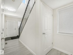 Entryway featuring light wood-finish flooring and a staircase with dark metal railings - 