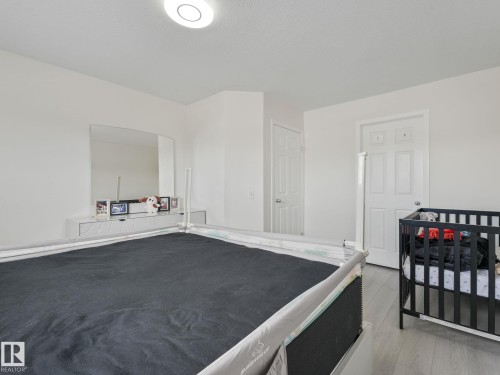 Interior room featuring wood-finish flooring and bright white walls - 18 230 Edwards Drive, Edmonton, AB 