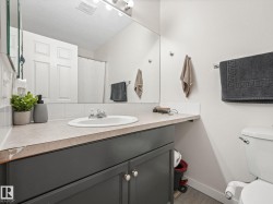 Bathroom vanity featuring a drop-in sink, dark cabinetry with chrome hardware, an expansive mirror, and overhead strip lighting - 