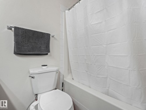 White ceramic toilet with chrome flush handle - 18 230 Edwards Drive, Edmonton, AB 