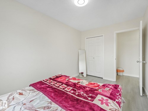 Room featuring light gray wood-finish flooring, white walls, a flush-mount ceiling light, and a double bi-fold closet door - 18 230 Edwards Drive, Edmonton, AB 