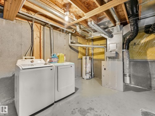 Utility area featuring concrete walls, exposed ceiling joists, and a painted concrete floor - 18 230 Edwards Drive, Edmonton, AB 