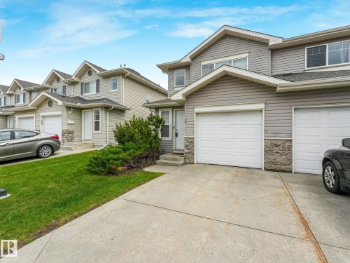 Contemporary multi-unit dwelling with light gray siding and stone accenting - 18 230 Edwards Drive, Edmonton, AB 