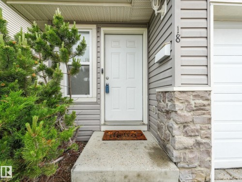 Entryway featuring a white paneled door with a contemporary smart lock, sidelight window, and a concrete stoop - 18 230 Edwards Drive, Edmonton, AB 