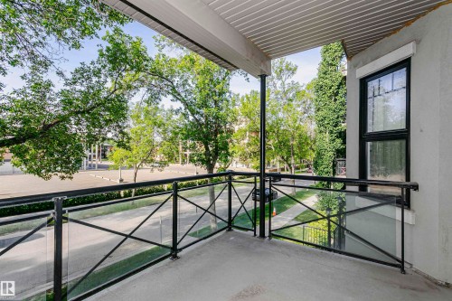 Private balcony featuring a concrete floor, black metal railing with glass inserts, and an overhead soffit - 211 10808 71 Avenue, Edmonton, AB 