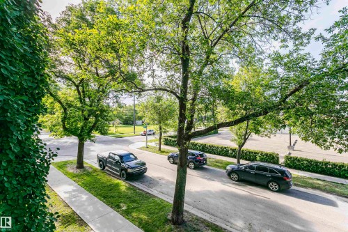 Streetscape featuring mature trees, a paved roadway, and concrete sidewalks - 211 10808 71 Avenue, Edmonton, AB 