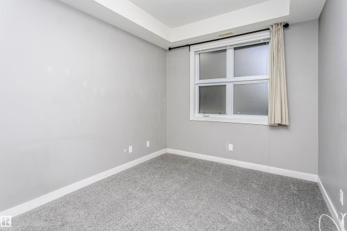 Room featuring light gray walls, white trim, and gray carpeting - 211 10808 71 Avenue, Edmonton, AB 