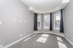 Bay window with three individual windows, light gray walls, dark gray carpeting, and white baseboards - 