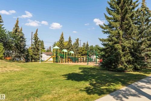 Community greenspace featuring a modern playground structure with slides and swings - 211 10808 71 Avenue, Edmonton, AB 