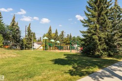 Community greenspace featuring a modern playground structure with slides and swings - 