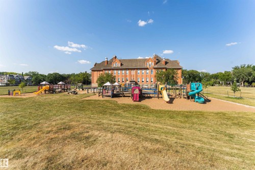 Expansive outdoor recreational area featuring multiple colorful playground structures, a large wood chip base, and surrounding grassy fields - 211 10808 71 Avenue, Edmonton, AB 