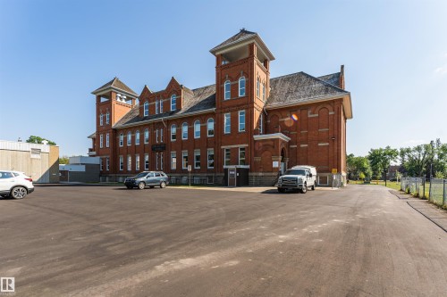Historic red brick building featuring two prominent towers, multiple windows, and an arched entry - 211 10808 71 Avenue, Edmonton, AB 