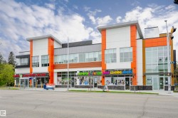 Modern commercial building featuring multiple storefronts, a prominent orange and white facade, expansive window displays, contemporary architectural lines, and a visible street-front presence - 
