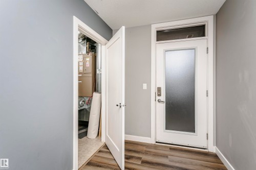Entry door with a frosted glass panel and transom window, complemented by wood-finish flooring - 211 10808 71 Avenue, Edmonton, AB 