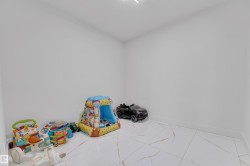 Spacious room featuring white walls, white baseboards, and large format white tile flooring with gold-tone veining - 