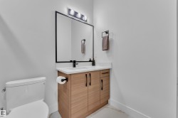 Powder room featuring a wood-finish vanity with black hardware, white countertop, and an undermount sink - 