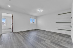 Spacious room featuring wood-finish flooring, white walls, and a contemporary ceiling light fixture - 